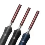 Parapluie homme chic avec manche en bois, disponible en noir, bleu et gris, alliant élégance et protection contre la pluie.