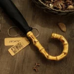 Parapluie homme élégant avec poignée en bambou et toile noire, posé sur du bois, accessoire stylé de la [Collection].