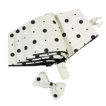 Parapluie pliant anti-UV motif pois noirs sur fond blanc avec nœud, élégant et pratique pour se protéger de la pluie et du soleil.