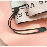 Parapluie automatique élégant noir, design moderne, accessoire en caoutchouc, posé sur fond pastel rose, parfait pour tous les styles.