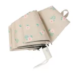 Parapluie automatique motif floral beige avec poignée blanche, alliant élégance et praticité pour vos journées pluvieuses.