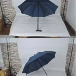 Parapluie canne bleu avec poignée réglable, présenté ouvert sur fond neutre avec mur en pierre, design élégant et pratique.