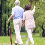 Parapluie canne semi-automatique rouge, élégant et pratique, parfait pour vos balades, ici porté par un couple dans un parc.