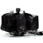 Parapluie cloche zèbre, design élégant en rayures noires et blanches, ouvert pour une protection optimale contre la pluie.