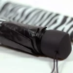 Parapluie cloche zèbre noir élégant, design unique, idéal pour un look tendance et chic, posé sur un fond à motifs zébrés.