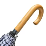 Parapluie élégant avec poignée bois et motif zigzag noir et blanc, parfait pour allier protection et style sous la pluie.