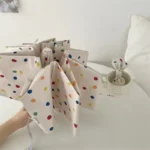 Parapluie femme à pois coloré ouvert sur une table avec tasse assortie, parfait pour rester stylée et protégée sous la pluie.