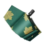 Parapluie pliant vert avec motifs feuillage doré, compact et élégant, parfait pour allier protection et style sous la pluie.