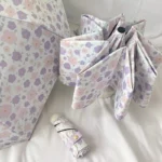 Parapluie pliant violet avec motif floral pastel, élégant et pratique, accompagné d'une housse, parfait pour une protection stylée.