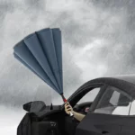 Parapluie tempête double couche ouvert, résistant à la pluie intense, utilisé depuis une voiture pour rester au sec.