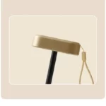 Parapluie de luxe intérieur vintage avec poignée dorée élégante et dragonne, accessoire chic sur fond beige.