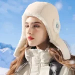 Femme avec capuche de pluie doublée en fausse fourrure beige, idéale pour l'hiver, dans un paysage enneigé sous un ciel bleu.