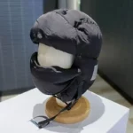 Capuche de pluie style aviateur, casque noir avec protection faciale pour le froid et la pluie, design moderne et fonctionnel.