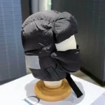 Capuche de pluie style aviateur en tissu noir avec visière intégrée, idéale pour affronter les intempéries avec style.