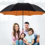 Famille sous un parapluie XXL noir et orange de 185 cm, protection élégante et pratique pour vos journées pluvieuses.
