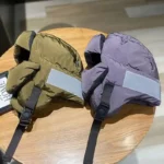 Gants de pluie style aviateur en vert olive et violet, bandes réfléchissantes, sangles ajustables, présentés sur table en bois.