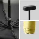 Parapluie compact avec poignée noire et couverture jaune repliée, design moderne et pratique pour toutes les collections.
