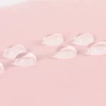 Mini parapluie léger résistant à l'eau avec gouttes translucides sur tissu rose, idéal pour protection élégante contre la pluie.