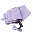 Parapluie pliant violet à motifs floraux blancs, automatique et élégant, idéal pour femme. Compact avec poignée noire et nœud assorti.
