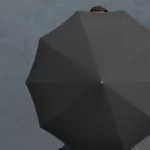 Parapluie avec lumière LED, design élégant noir, ouvert sur fond gris texturé, protection innovante et pratique pour la pluie.