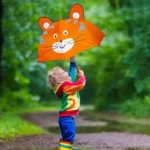 Enfant souriant tenant un parapluie orange tête de chat sous la pluie, style animalier, idéal pour enfants, collection [Collection].