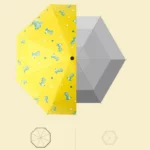 Parapluie enfant jaune avec motifs dinosaures et étoiles, idéal pour égayer les jours de pluie avec style et protection.