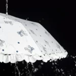 Parapluie femme chic avec motif à pois et détails nœuds, résistant à la pluie, parfait pour allier style et praticité.