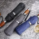 Parapluies golf chic repliés, noir, gris et bleu, avec poignées bois et finitions métalliques raffinées, parfaite élégance.