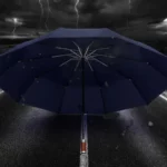 Parapluie golf chic bleu ouvert sur une route sous un ciel orageux avec éclairs, alliant protection et élégance sous la pluie.
