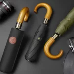 Parapluie homme pliant élégant avec poignée en bois, étui noir inclus, design sophistiqué sur fond sombre, parfait pour toutes saisons.