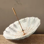 Parapluie japonais longue poignée avec motif d'arbres délicat, posé ouvert sur une surface en jute, style élégant et raffiné.