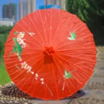 Parapluie japonais rouge vintage avec motifs floraux, design élégant et artisanal, parfait pour une ambiance traditionnelle et raffinée.