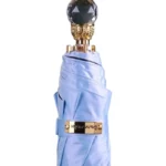 Parapluie luxe satin bleu avec poignée dorée et pommeau cristal, alliant élégance et efficacité pour une protection contre la pluie.