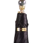 Parapluie luxe noir avec poignée dorée et cristal, design raffiné, parfait pour un style élégant et protection optimale.