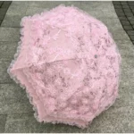 Parapluie mariage vintage en dentelle rose avec motifs floraux, élégance romantique, parfait pour un mariage ou une séance photo.