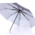 Parapluie original rayé gris et blanc, design élégant, structure noire robuste, parfait pour se protéger de la pluie avec style.