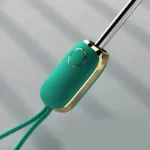 Parapluie pliant coloré avec manche turquoise et bouton doré, alliant design élégant et moderne pour une protection stylée contre la pluie.