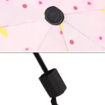 Parapluie pliant rose à motifs fleuris, compact et élégant, avec mécanisme de fermeture robuste et tige noire renforcée.