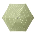 Parapluie vert à pois blancs, compact et élégant, parfait pour une protection stylée contre la pluie.