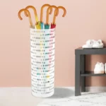 Porte parapluie cylindrique blanc avec plusieurs parapluies colorés, poignées en bois, idéal pour une entrée moderne et organisée.