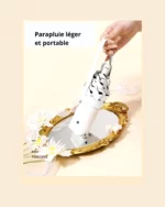 Parapluie femme chic et léger, design élégant tenu sur fond fleuri, parfait pour compléter un style raffiné et moderne.