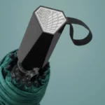 Parapluie à trois plis élégant avec poignée noire texturée, design moderne, idéal pour la collection [Collection], fond pastel.