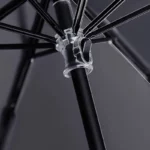 Parapluie à trois plis, design moderne, structure en métal noir robuste et support transparent, polyvalent pour toute occasion.