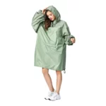 Poncho femme à manches longues vert pastel avec capuche et poche avant, parfait pour les journées pluvieuses et élégantes.