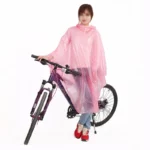 Femme avec poncho de pluie transparent à pois roses près d'un vélo, combinaison mode pratique pour pluie et cyclisme.
