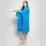 Femme souriante portant un poncho femme léger bleu, design moderne, idéal pour la pluie, présenté sur fond neutre.