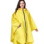 Femme portant un poncho de pluie jaune avec capuche, parfait pour la randonnée et la protection contre la pluie en extérieur.