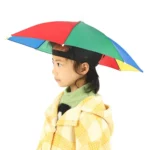 Petite fille avec chapeau parapluie coloré, ludique et pratique, parfait pour protéger les enfants de la pluie avec style.