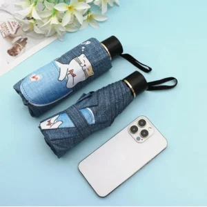 Parapluie automatique pliable en denim avec motifs amusants, fond bleu, accessoire moderne idéal pour les journées de pluie.