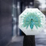 Parapluie automatique paon avec motif coloré, parfait sous la pluie, capturé sur un fond urbain flou pour un style élégant.